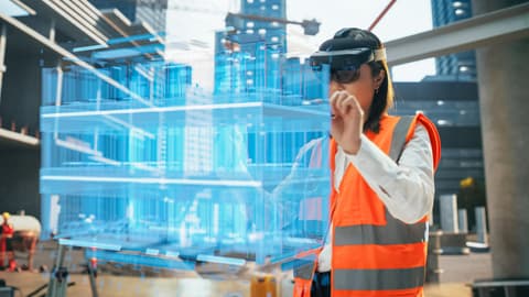 A female construction worker examines digital plans.